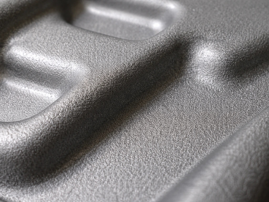 Macro close-up of textured cast aluminum with a smooth powder-coat finish and subtle molded dimples.